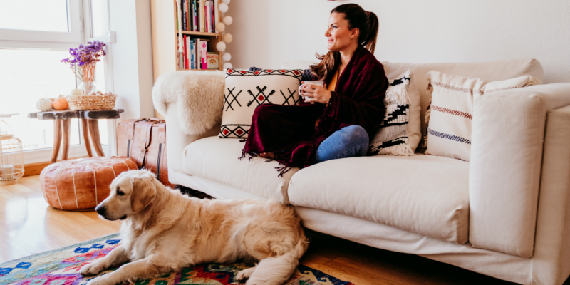 Woman relaxing on sofa with tea and dog