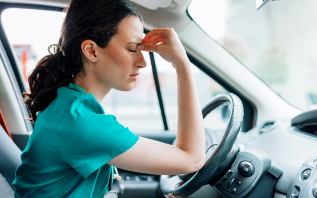 Doctor sitting in vehicle with hand on head