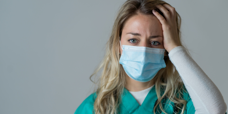 Doctor wearing mask holding hand on forehead