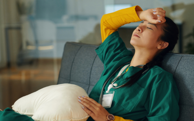 Nurse sitting on couch with wrist on forehead